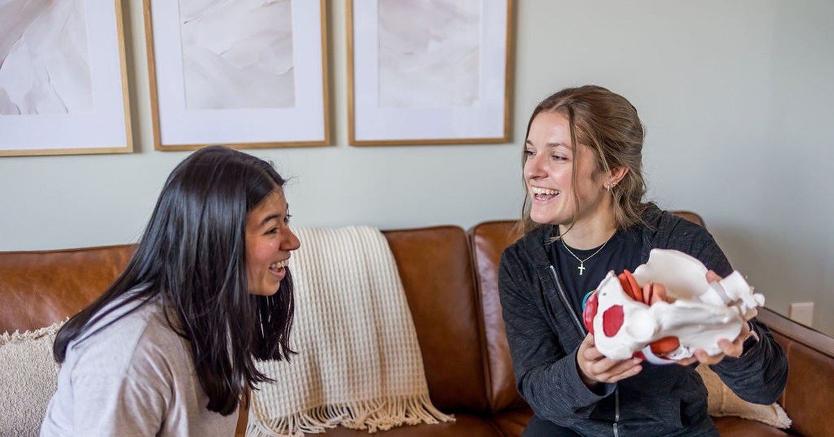 Courtney Teehan explaining pelvic floor anatomy with a pelvis model to a client on the couch at the Whole Health Solutions Pelvic Health Center